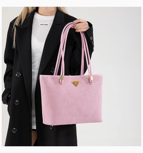 Detail of pink suede tote bag with signature gold triangle logo and slim shoulder straps