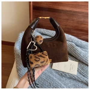 Detail of dark brown matte hobo bag with leopard print pom-pom and woven rope charms