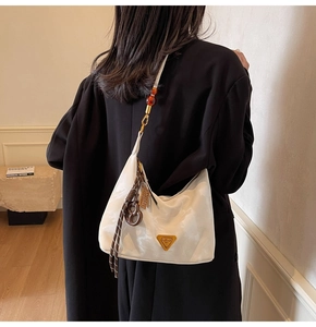 Dettaglio della borsa in nylon crema con placca dorata e perline ambrate sul manico