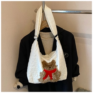 Detail der weißen Stepptasche mit süßem braunem Plüschbär und roter Schleifenverzierung