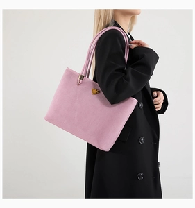 Detailed view of pink suede tote bag with gold triangle ornament and thin shoulder straps