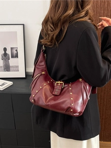 Retro burgundy shoulder bag with gold studs and fringe tassel detail worn by model