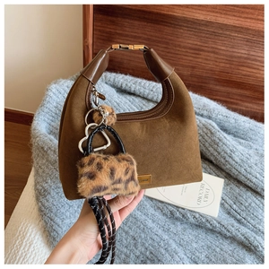 Detail of dark brown suede dumpling bag with leather handle and leopard print charm