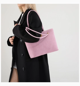 Detail of pink suede tote bag with golden lock on black coat lifestyle shot