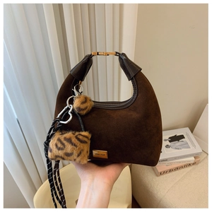 Detailed macro of dark brown suede hobo bag with gold hardware and leopard charm