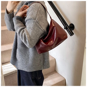 Close-up of glossy dark red PU leather shoulder bag with sleek minimalist texture
