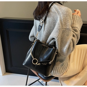 Détail du sac seau noir avec chaîne dorée et bandoulière à motif pied-de-poule élégant