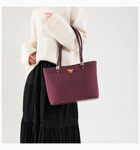 Detail of burgundy suede tote bag with golden triangle hardware on white background