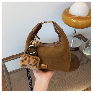 Detail of brown suede dumpling bag featuring leopard print charm and Miss Mail logo