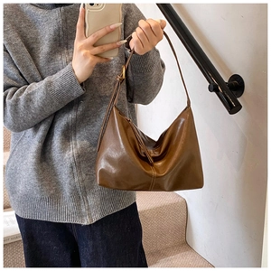 Detail of soft brown leather tote bag with adjustable strap and textured finish