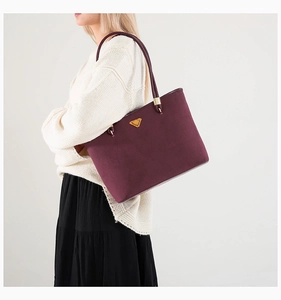 Detail of burgundy leather tote bag with gold triangle logo and top handles for women