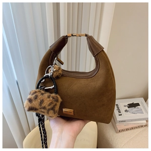 Brown suede crescent bag detail featuring gold metal handle and leopard faux fur pendant
