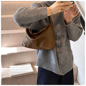 Detail view of a large vintage brown leather hobo bag held by a model in a cozy setting