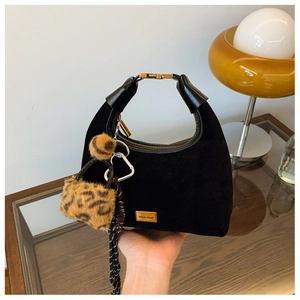 Detail shot of black matte dumpling bag with leopard pompom and gold brand hardware