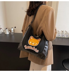 Gros plan d'un sac bandoulière noir en cuir avec patch ours et bandoulière en chaîne