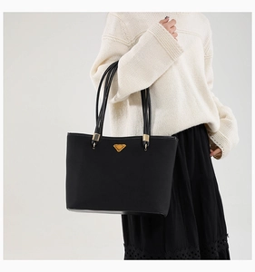 Detail of black tote bag featuring unique multi-strand straps and golden triangular hardware