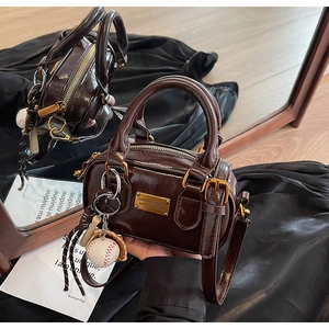 Detail of vintage brown patent leather pillow bag with gold hardware and baseball charm