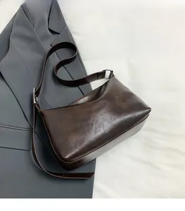 Detail view of dark brown retro pillow bag with natural leather texture and silver buckle