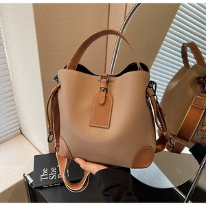 Macro detail of caramel pebbled leather bucket bag with wide strap and side mirror view
