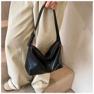 Detailed view of the shiny black leather shoulder bag with gold hardware buckle