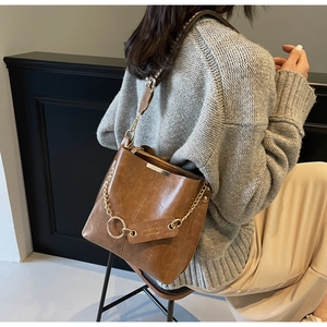 Détail du sac seau en cuir caramel avec chaîne dorée et renfort métallique sur le haut