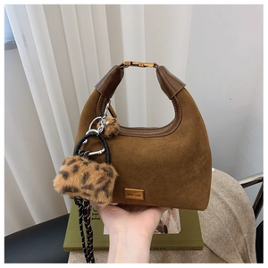 Close-up of brown suede hobo bag with gold buckle handle and leopard plush charm