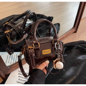 Detail of vintage brown mini Boston bag with glossy finish and baseball charm on silk