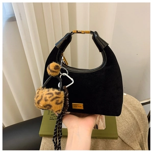 Detail of black matte dumpling bag with gold hardware and leopard print charm