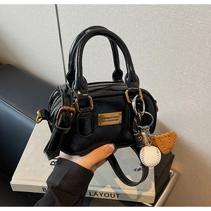 Close-up of black glossy bowling bag with gold hardware and creative baseball charm