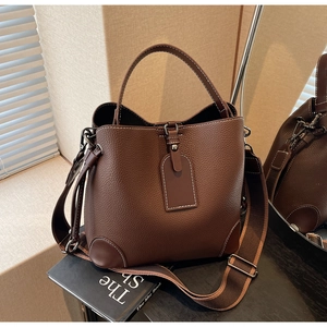 Detail of dark brown leather bucket bag with contrast stitching and wide shoulder strap