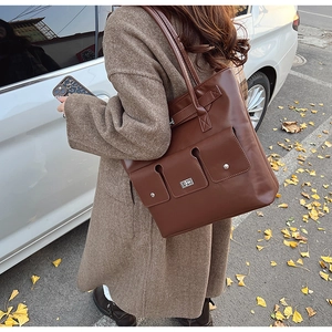 Détail d'un sac cabas en cuir PU marron avec poche frontale fonctionnelle et fermoir argenté