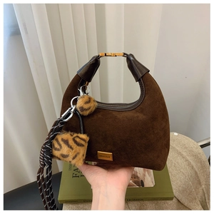 Detail of dark brown suede hobo bag with gold buckle, leopard charm and woven cord accents