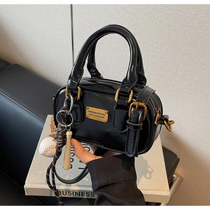 Detail of glossy black patent leather mini Boston bag with gold hardware and baseball charm