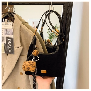 Close-up of black suede hobo bag with gold Miss Wait plaque and leopard print charms