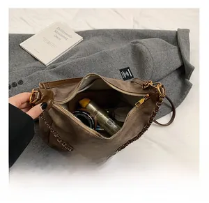 Top view of brown suede tote bag interior with metal chain and cosmetics inside