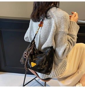 Detail of black crescent hobo bag with amber beads and decorative woven knot