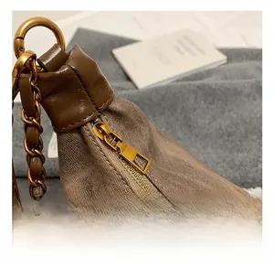 Macro detail of textured brown tote bag featuring golden zipper and high-quality chain strap