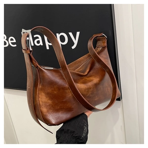 Close-up of vintage brown leather pillow bag featuring a wide adjustable shoulder strap
