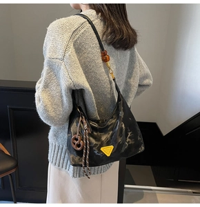 Detail of black marble texture handbag with yellow triangle logo and amber beads