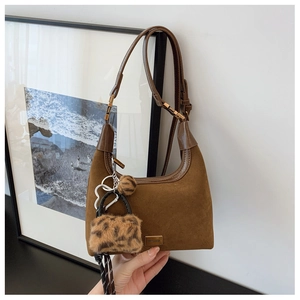 Detail of a brown suede hobo bag with adjustable strap and a leopard print faux fur charm