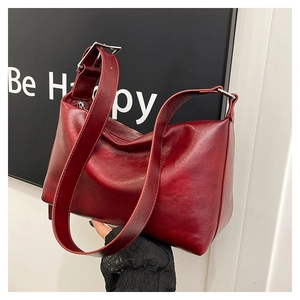 Detail of dark red vintage leather pillow bag with silver buckle and wide strap