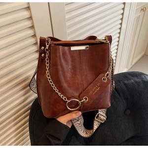 Détail d'un sac seau vintage marron avec chaîne en métal et bandoulière tissée large