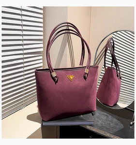 Detail view of burgundy tote bag with gold triangle hardware and long shoulder straps
