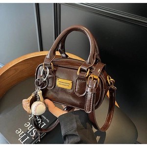 Detail of dark brown glossy patent leather mini Boston bag with baseball pendant