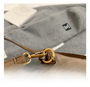 Close-up of premium golden metal hook and lobster clasp on dark brown tote bag