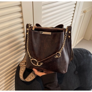 Détail d'un sac seau vintage marron avec bandoulière jacquard et détails chaîne dorée