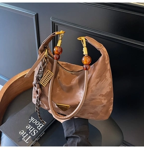 Detail of brown nylon hobo bag with amber resin bead handle and golden abacus charm