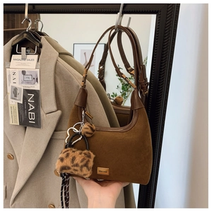 Detail of a brown matte suede dumpling bag with a stylish leopard print plush charm