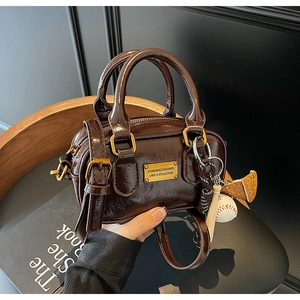 Close-up of a dark brown glossy patent leather mini Boston bag with gold hardware detail