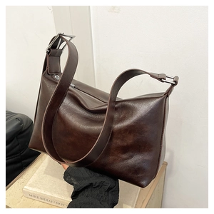 Detail of the dark brown leather texture with metallic zipper and adjustable wide strap